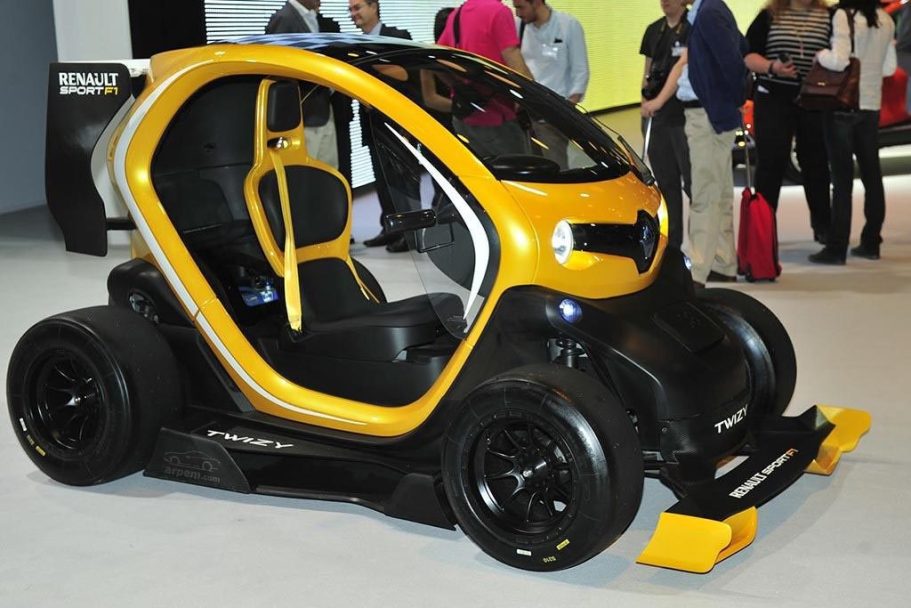 Coche eléctrico compacto de diseño futurista en un evento. Color amarillo y negro.