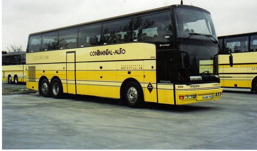 Autobús amarillo y negro estacionado en un área con otros autobuses de fondo.