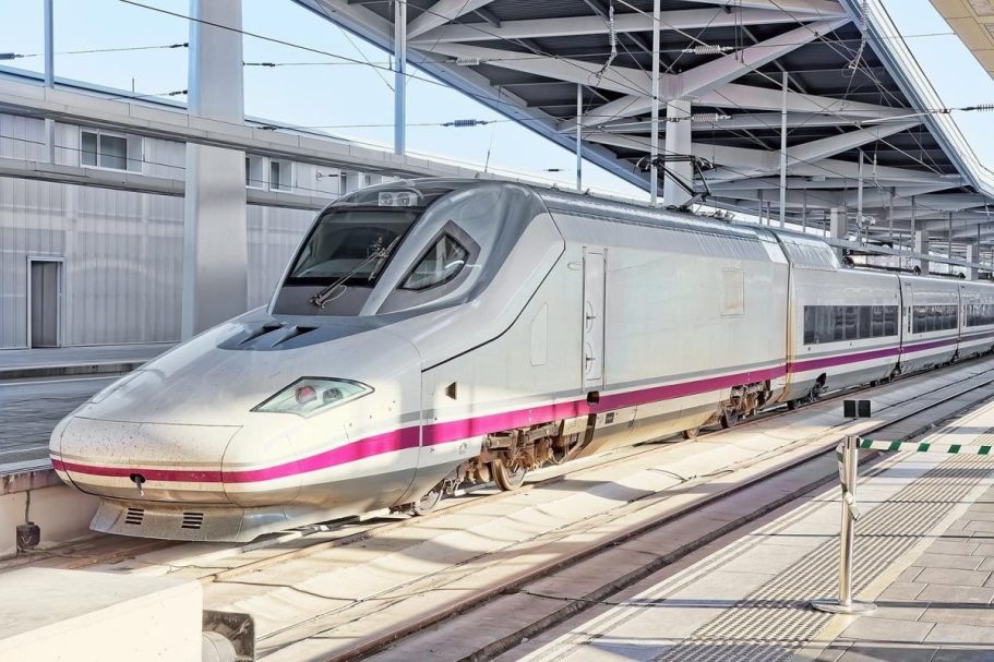 Tren de alta velocidad en una estación moderna, con diseño aerodinámico y colores claros.