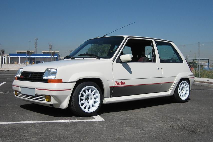 Coche compacto de color blanco con detalles rojos y llantas blancas estacionado al aire libre.