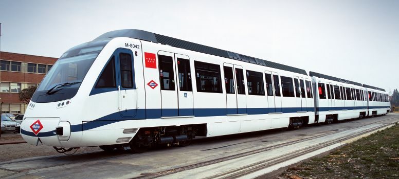 Tren moderno de metro, blanco y azul, estacionado en la vía.