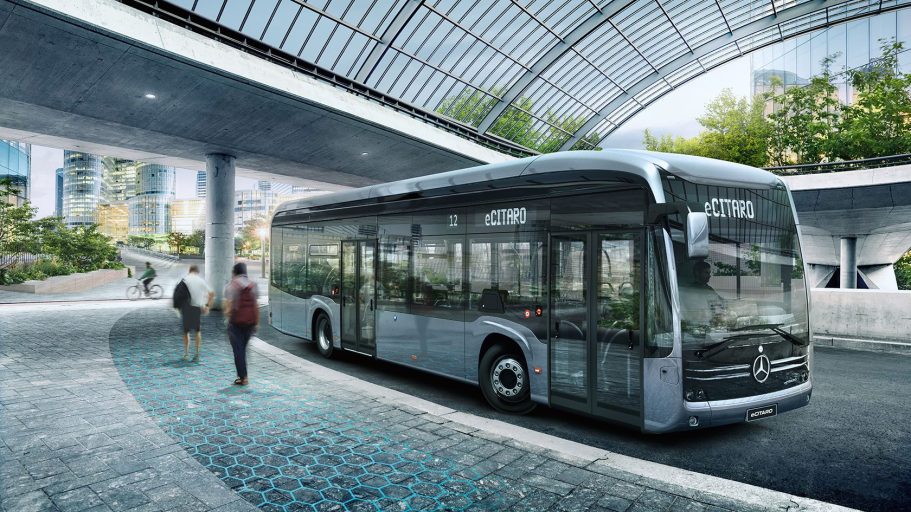 Autobús urbano moderno en una estación con arquitectura contemporánea y vegetación.
