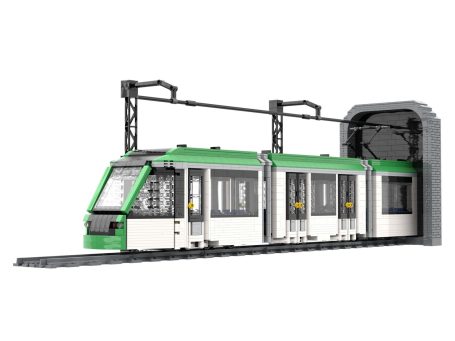 Tranvía de juguete blanco y verde saliendo de un túnel con catenaria y vía.