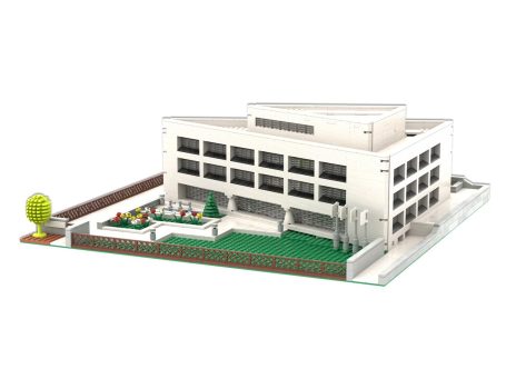 Edificio moderno con jardín y área recreativa, diseño minimalista y estructura blanca.