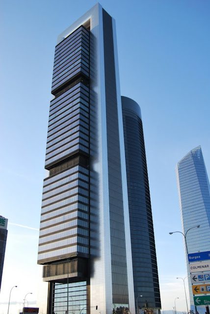 Rascacielos moderno con fachadas de vidrio y estructura metálica en un cielo despejado.