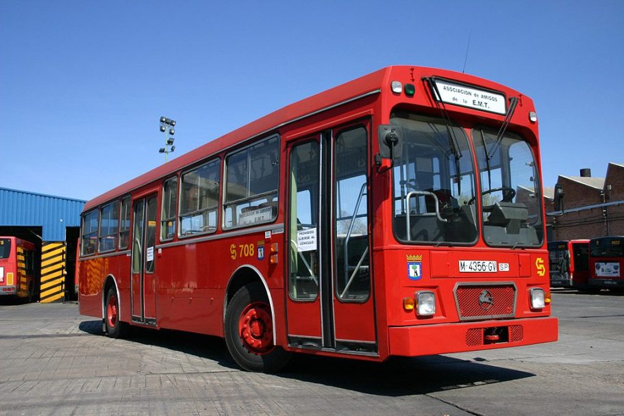 Autobús rojo clásico en un aparcamiento con cielo despejado.